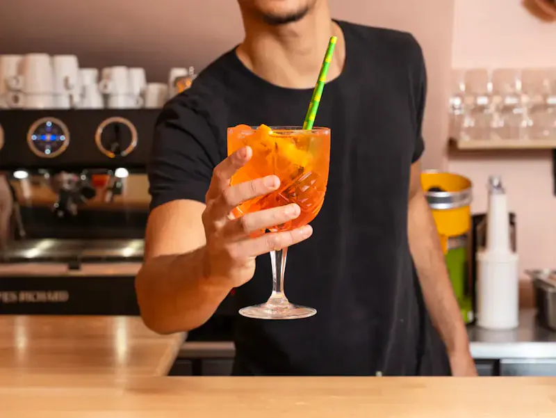Cocktail italien Aperol Spritz pétillant avec eau gazeuse, présenté sur une table de restaurant dans le quartier animé de Châtelet les Halles à Paris.