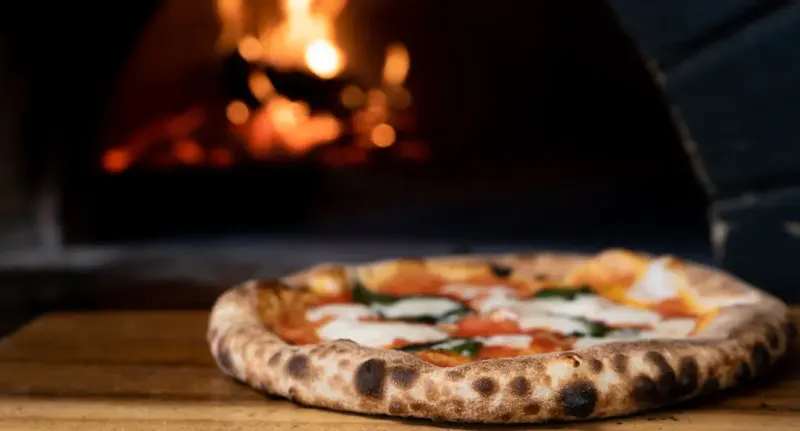 pizza on brown wooden table | Photo by Nik Owens, on https://unsplash.com/@nik_owens?utm_source=centralapp&utm_medium=referral