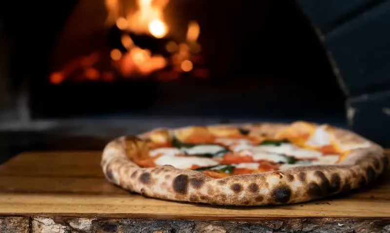 pizza on brown wooden table | Photo de Nik Owens, sur https://unsplash.com/@nik_owens?utm_source=centralapp&utm_medium=referral
