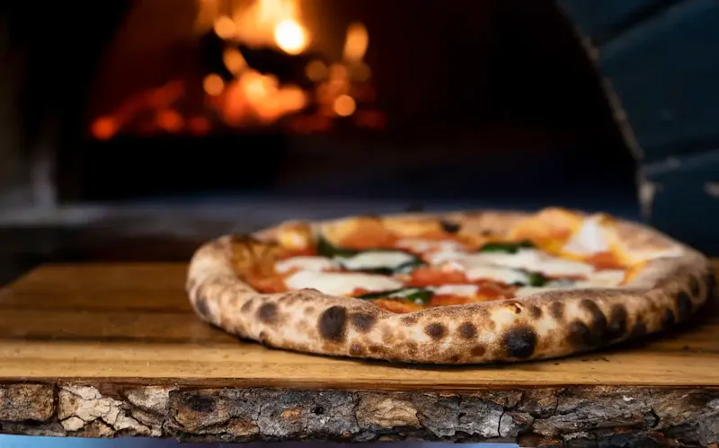 pizza on brown wooden table | Photo by Nik Owens, on https://unsplash.com/@nik_owens?utm_source=centralapp&utm_medium=referral