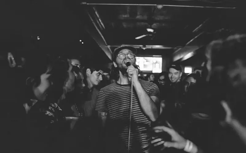Image of La Prise 1789 man holding microphone | Photo by Steven Aguilar, on https://unsplash.com/@eysteve?utm_source=centralapp&utm_medium=referral