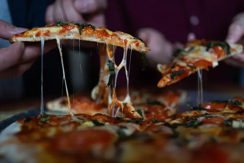 person picking sliced pizza | Photo by Brenna Huff, on https://unsplash.com/@brenna_lynn?utm_source=centralapp&utm_medium=referral