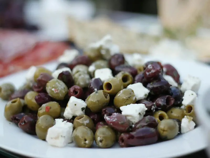 A close-up of a delicious olive and feta salad on a white plate, perfect for healthy meals. | Photo by Kate, on https://www.pexels.com/@kate-3513459?utm_source=centralapp&utm_medium=referral