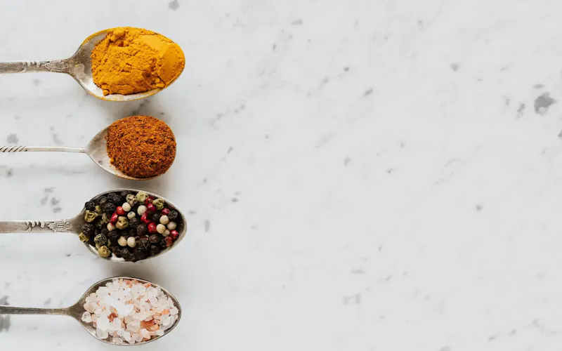 An assortment of colorful spices on spoons laid on a marble surface. | Photo by Photo By: Kaboompics.com, on https://www.pexels.com/@karolina-grabowska?utm_source=centralapp&utm_medium=referral