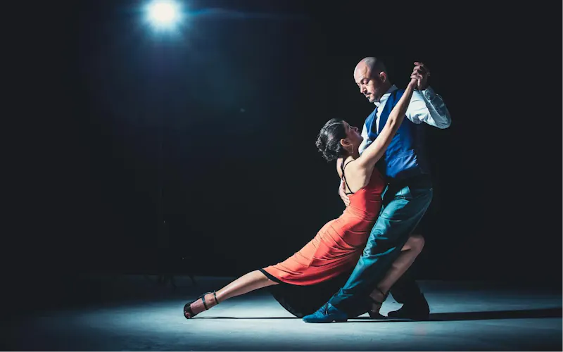 Elegant couple performing tango under a dramatic spotlight, showcasing passion and grace. | Photo by Marko Zirdum, on https://www.pexels.com/@marko?utm_source=centralapp&utm_medium=referral