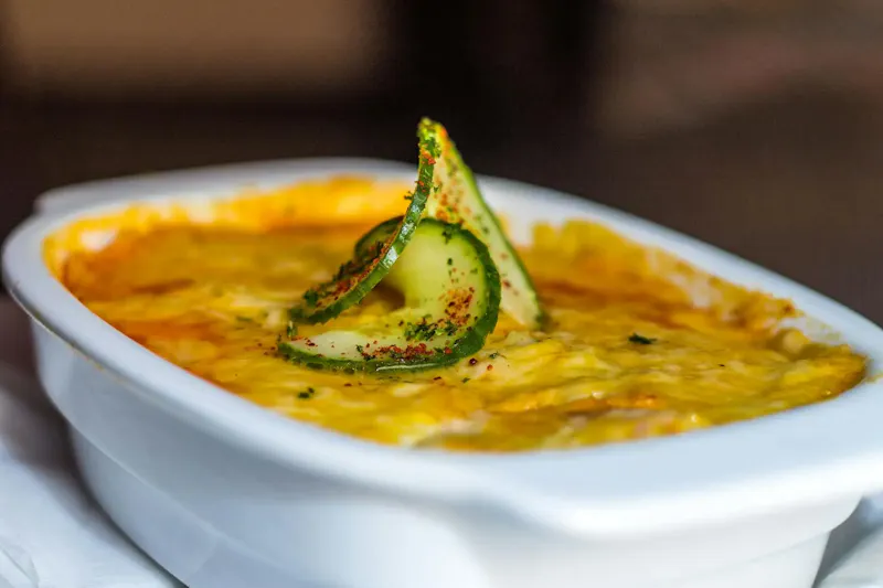 Close-up of a cheesy lasagna topped with cucumber slices, showcasing rich Italian flavors. | Photo de Edwin Jaulani, sur https://www.pexels.com/@jaulani7?utm_source=centralapp&utm_medium=referral