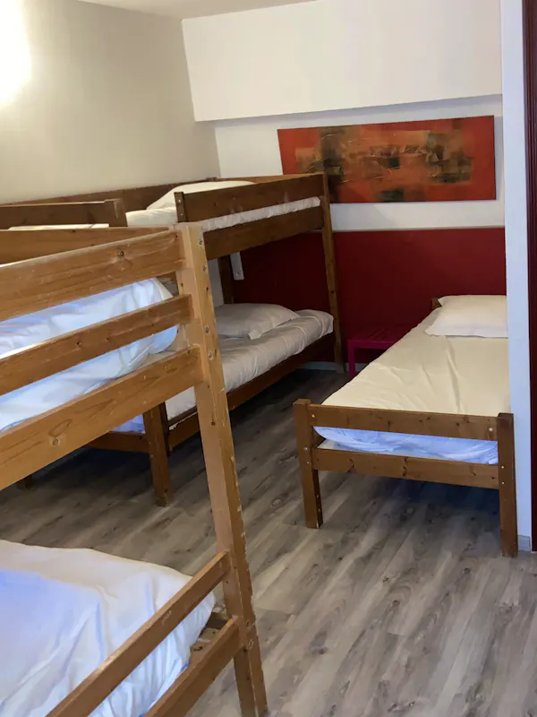 Chambre confortable pour six personnes, équipée de lits simples et de lits superposés, avec salle de bain et toilettes privatives. Petit-déjeuner inclus.
