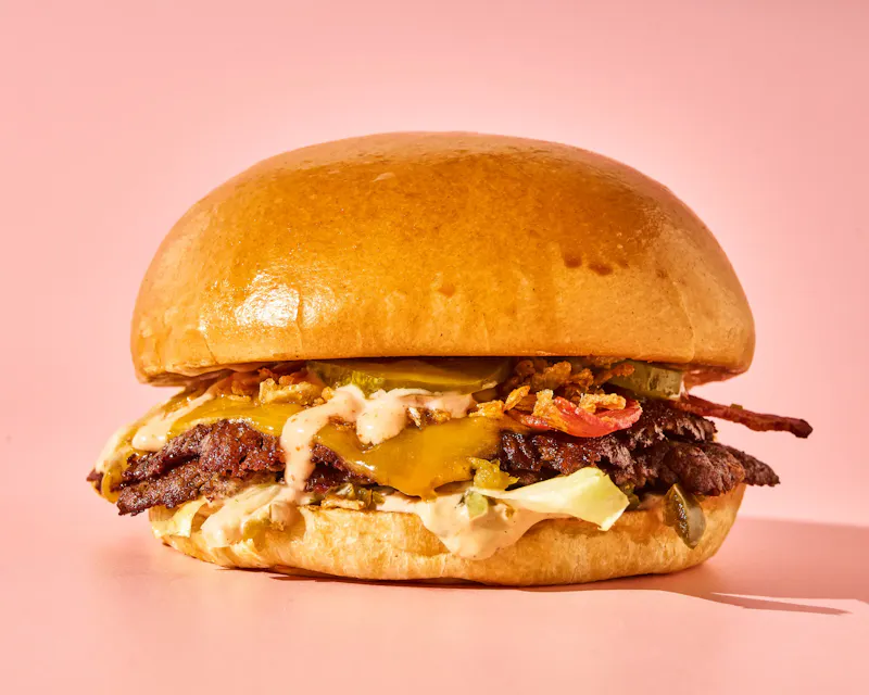 Smash burger au bœuf Charolais et cheddar maturé avec bacon et oignons crispy, sauce miel-BBQ, servi chez Buns Ourcq, Paris 15 et Vannes