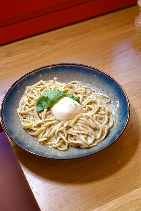 Linguine al Tartufo du restaurant Ti Amo : des pâtes fraîches liées à une crème de truffe onctueuse, parsemées de parmesan et de mozzarella, surmontées d'une burrata entière crémeuse pour une expérience gourmande.