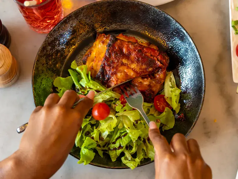 Gros plan sur une lasagne bolognese savoureuse avec sa viande Halal, accompagnée d'une salade croquante. À déguster dans l'ambiance chaleureuse du restaurant Ti Amo Place d'Italie.