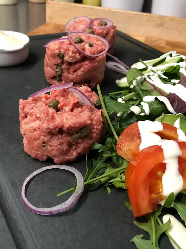 Un steak tartare accompagné de salade fraîche et sauce. Un steak tartare accompagné de salade fraîche et sauce.