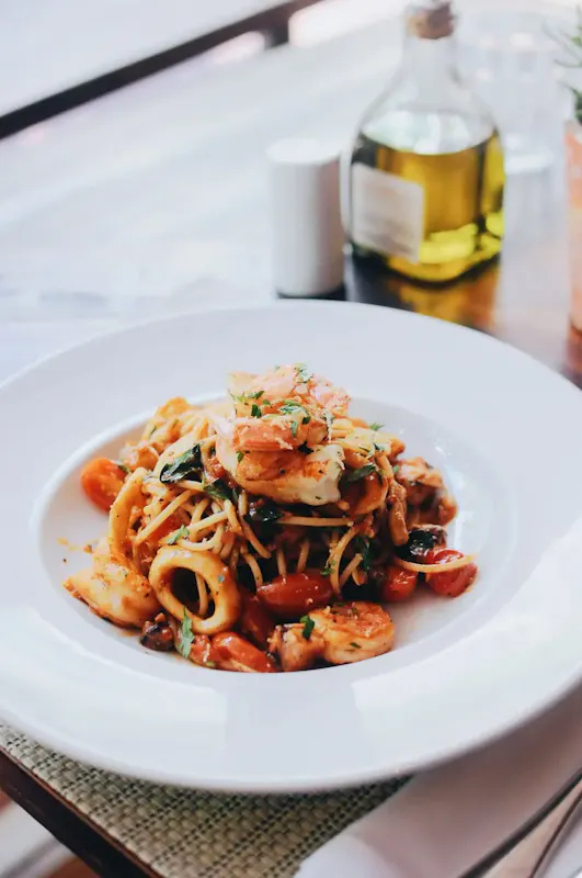 Plate of spaghetti with shrimp and calamari garnished with herbs, captured indoors. | Photo by Desativado, on https://www.pexels.com/@igrejapreta?utm_source=centralapp&utm_medium=referral