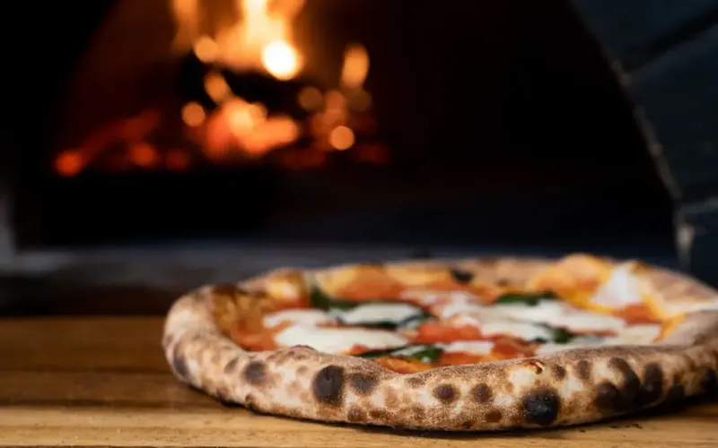 pizza on brown wooden table | Photo by Nik Owens, on https://unsplash.com/@nik_owens?utm_source=centralapp&utm_medium=referral