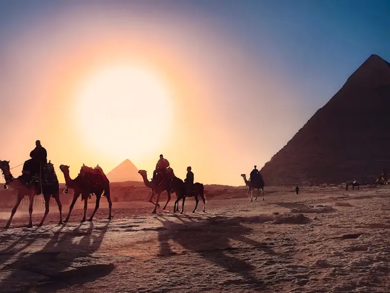 five persons riding camels walking on sand beside Pyramid of Egypt | Immagine di simon, su https://unsplash.com/@simon_berger?utm_source=CentralApp&utm_medium=referral