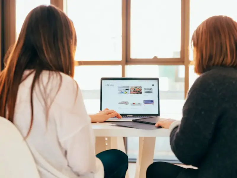 two women talking while looking at laptop computer | Photo de KOBU Agency, sur https://unsplash.com/@kobuagency?utm_source=centralapp&utm_medium=referral