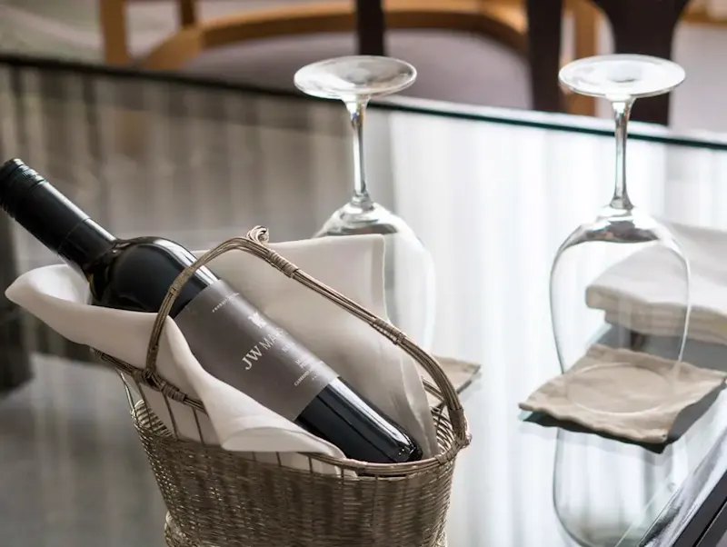 A glass table with a basket of wine and a bottle of wine | Foto door Antonio Araujo, op https://unsplash.com/@antonioaaaraujo?utm_source=centralapp&utm_medium=referral