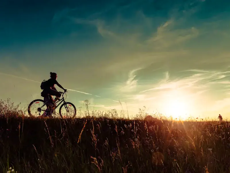 a person riding a bike in a field at sunset | Photo by Marianna Lutkova, on https://unsplash.com/@mery_lu_design?utm_source=CentralApp&utm_medium=referral